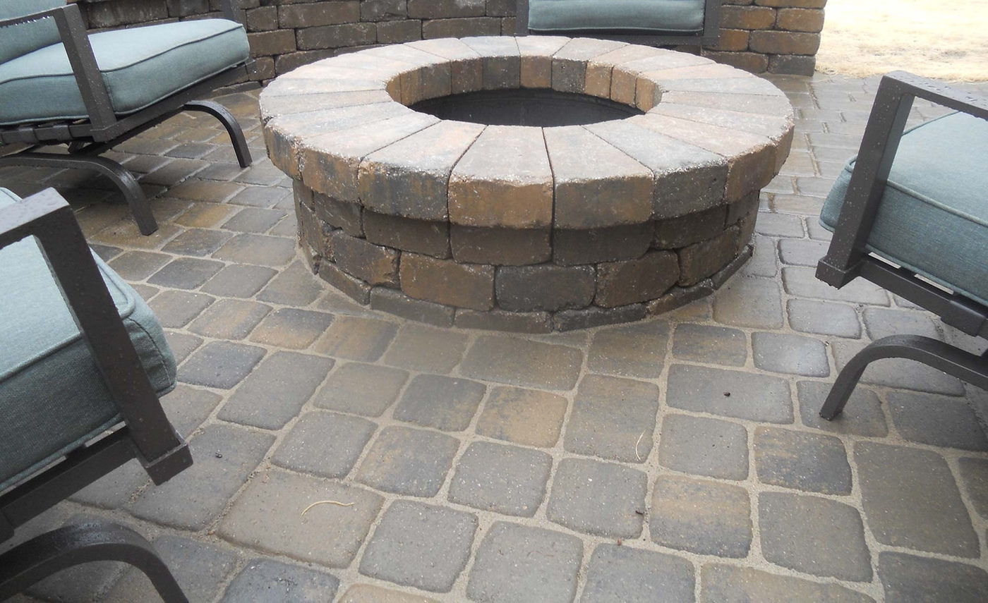 A finished paver patio with a stone fire pit built by Outlook Hardscape